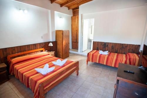 a bedroom with two beds and a dresser and a television at Iguazú Green Hotel in Puerto Iguazú