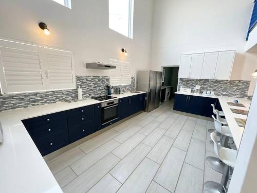 a large kitchen with blue cabinets and white tile floors at Dolphinbeach Seafront Villa in Langstrand
