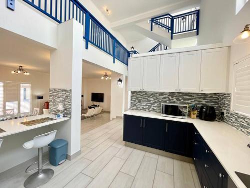a large kitchen with white cabinets and blue stairs at Dolphinbeach Seafront Villa in Langstrand