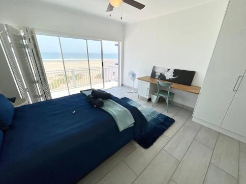 a bedroom with a blue bed with a view of the ocean at Dolphinbeach Seafront Villa in Langstrand