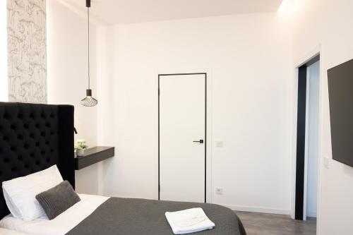 a bedroom with white walls and a bed with a black headboard at Luxury Apartments Laborca in Uzhhorod