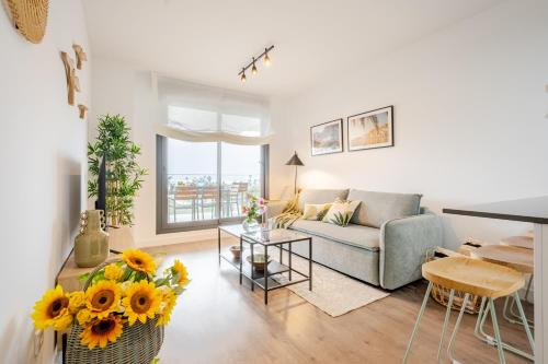 Una sala de estar con un sofá y una mesa con girasoles. en El Balconcito, en Torre del Mar