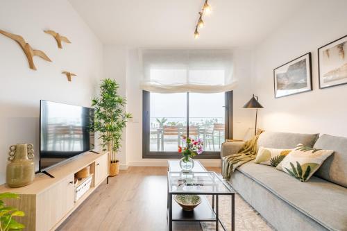 Una sala de estar con un sofá y un televisor. en El Balconcito, en Torre del Mar