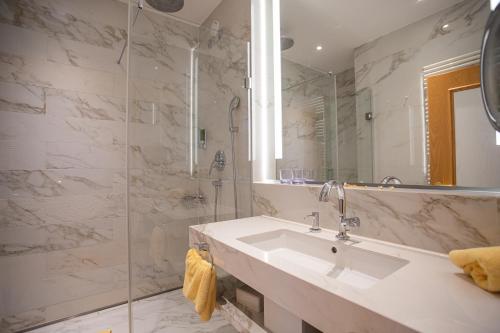 a bathroom with a sink and a shower at Thermenhotel Quellenhof in Bad Füssing