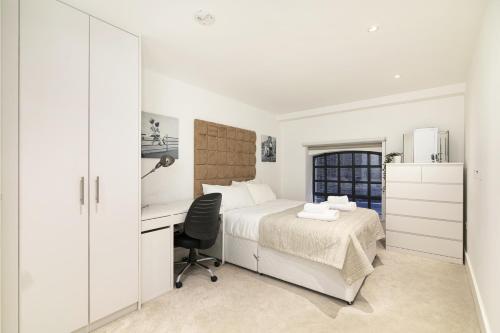 a white bedroom with a desk and a bed and a chair at Bull Inn Court - Walking distance to Covent Garden Square in London