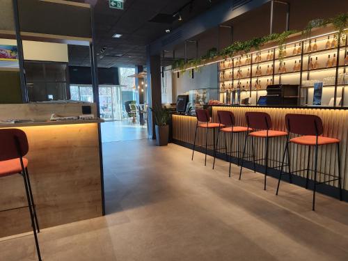 a bar with orange stools in a restaurant at Campanile La Roche Sur Yon Centre Gare in La Roche-sur-Yon