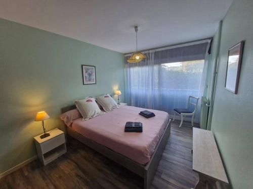 - une chambre avec un lit doté d'une couverture rose et d'une fenêtre dans l'établissement Les Coquelicots - Fréjus Plage, à Fréjus