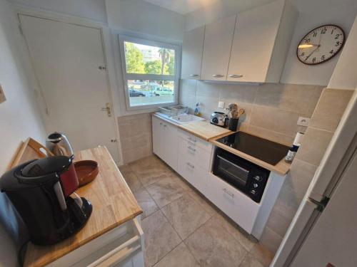 une cuisine avec un évier et une horloge murale dans l'établissement Les Coquelicots - Fréjus Plage, à Fréjus