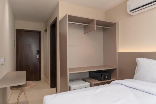 a bedroom with a white bed and a desk and a chair at Transamerica Dunas de Marapé in Jequia da Praia