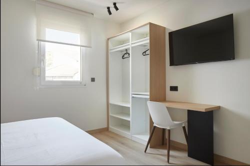 a bedroom with a desk and a tv on the wall at Pensión Pakeleku in Urnieta