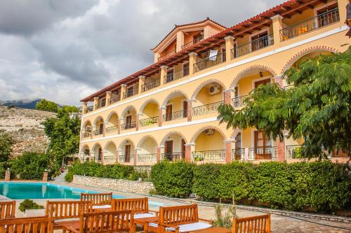 a large building with wooden benches in front of a pool at Apart-Hotel Llazari in Himare