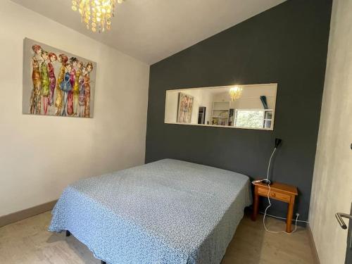 une chambre avec un lit bleu et un miroir dans l'établissement Grand T2 sous les pins, à Pourrières