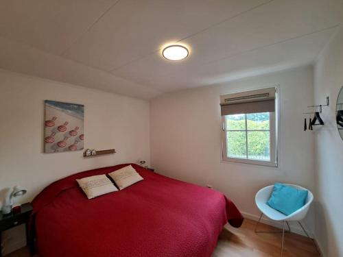 a bedroom with a red bed and a window at Villa Present - Chalet Heinkenszand VP008 in Heinkensand