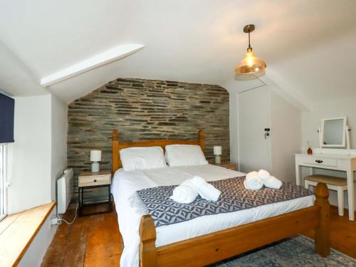 una camera con un grande letto con un muro di mattoni di Crab Cottage a Delabole