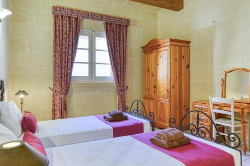 a bedroom with two beds and a window at Villagg tal-Fanal in Għasri