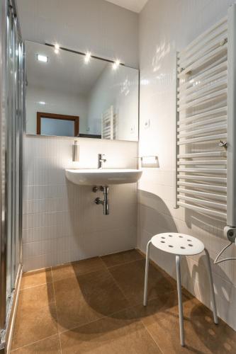 a white bathroom with a sink and a stool at Casa da Corujeira - Montalegre in Montalegre