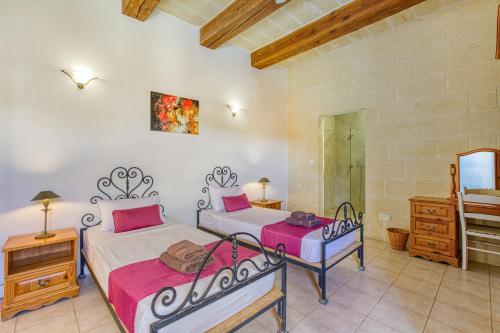 a bedroom with two beds and a dresser and a mirror at Villagg tal-Fanal in Għasri