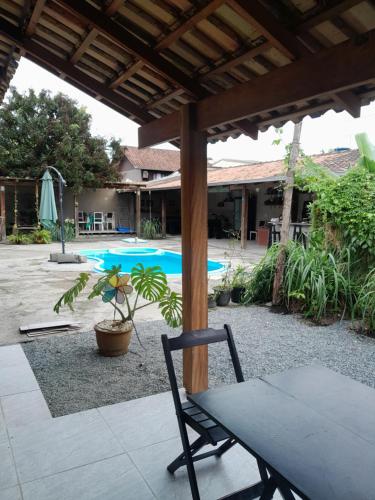 a patio with a table and a chair and a pool at Cabana Carambu 06 suíte in São Francisco do Sul