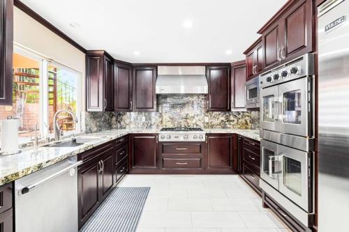 a kitchen with wooden cabinets and stainless steel appliances at Resort Home with Games, Slide, Oasis in Los Angeles