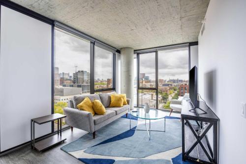 a living room with a couch and large windows at Freshly Minted 2BR - Elegance & Comfort in Central Chicago in Chicago