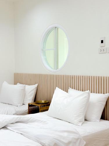 two beds with white sheets and a mirror on the wall at Cozy house in Sathani Hat Yai