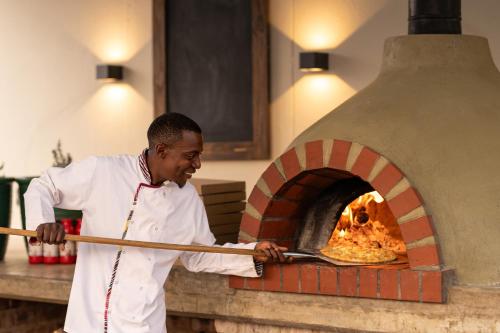 a man putting a pizza into an oven at Mercure Hotel Windhoek in Windhoek