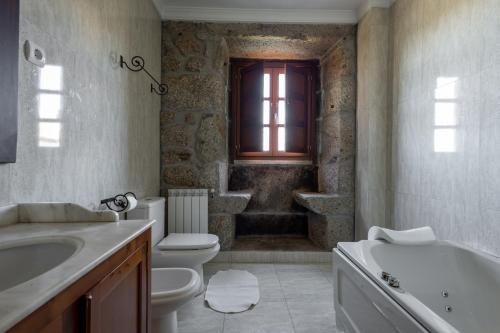 a bathroom with a toilet and a tub and a sink at Casa do Cerrado in Montalegre