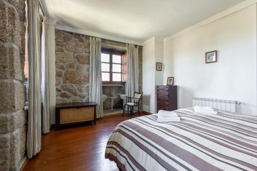a bedroom with a bed and a stone wall at Casa do Cerrado in Montalegre