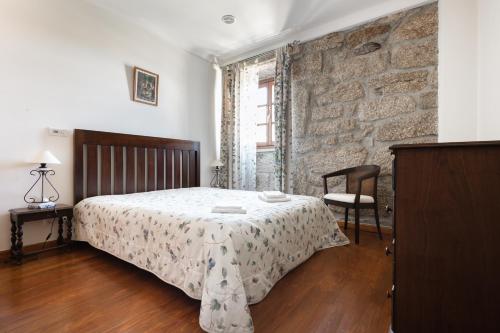 a bedroom with a bed and a brick wall at Casa do Cerrado in Montalegre
