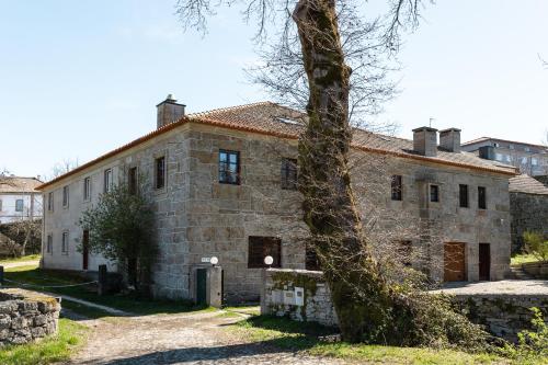 an old stone house with a tree in front of it at Casa do Cerrado in Montalegre