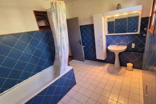 een blauwe betegelde badkamer met een wastafel en een douche bij T4 Furesta - Casa Mattea in Aléria
