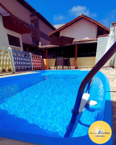 a swimming pool with a hose in front of a house at Pousada Gaivotas de Maranduba in Ubatuba
