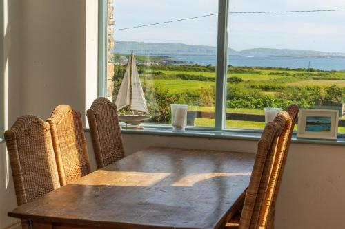 a dining room table with chairs and a window with a sailboat at Schull Coastal rural hideaway 5 night min in Derreennatra