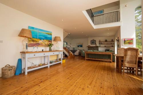 a living room with a wooden floor and a table at Schull Coastal rural hideaway 5 night min in Derreennatra