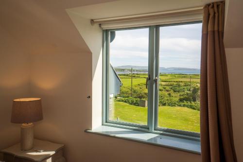 a window with a view of a green field at Schull Coastal rural hideaway 5 night min in Derreennatra