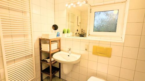 a white bathroom with a sink and a mirror at Gästewohnung Köln-Longerich in Cologne