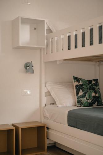 a white bedroom with a bunk bed and two tables at Casa Pirouette in Alassio