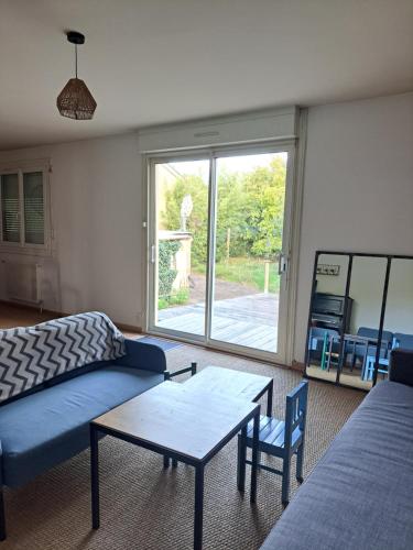 un salon avec un canapé, une table et une fenêtre dans l'établissement Gîte L'étape 6 chambres, à Redon
