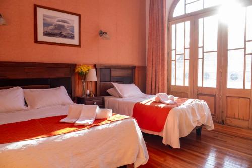 a hotel room with two beds and a window at Hotel Plaza in Punta Arenas