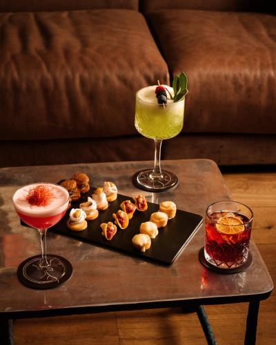 two cocktails and a tray of snacks on a table at Montana Lodge & Spa, by R Collection Hotels in La Thuile