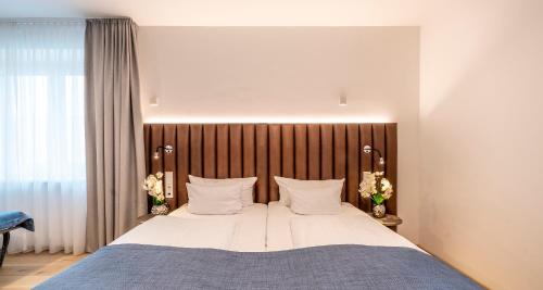 a bedroom with a large bed with a wooden headboard at Aiden by Best Western Biberach in Biberach an der Riß