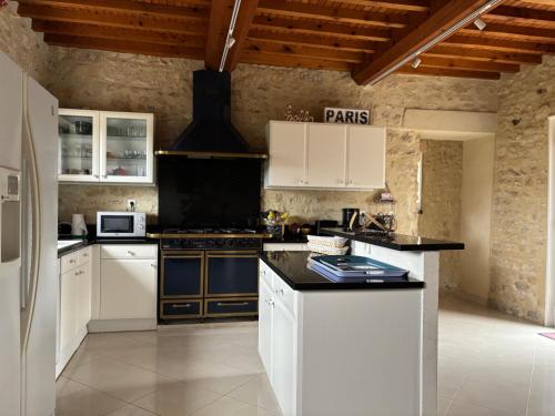 a kitchen with white cabinets and black counter tops at Le So Art, grande maison 4 chambres, terrain de pétanque, grand jardin clos, flipper, babyfoot, jeux Arcade, ping pong,1 km mer, proche golf, Port en Bessin, Bayeux et plages du débarquement, adaptée enfants in Commes