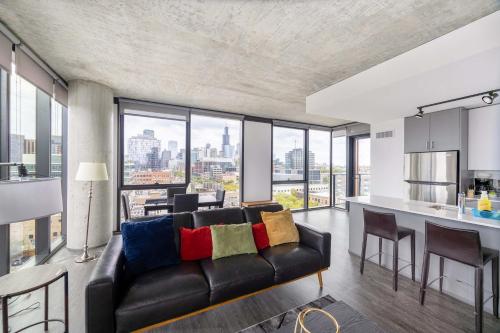 a living room with a black couch and a kitchen at Sophisticated 3BR Suite - New Modern and Luxurious in Chicago