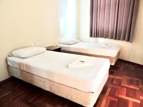 two beds in a room with wooden floors at Pouso Alegre Hotel INN - Próximo a Unimed e Rodoviária in Pouso Alegre