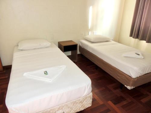 two beds in a room with white sheets at Pouso Alegre Hotel INN - Próximo a Unimed e Rodoviária in Pouso Alegre