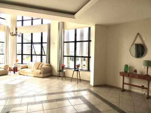 a living room with large windows and a couch at Pouso Alegre Hotel INN - Próximo a Unimed e Rodoviária in Pouso Alegre
