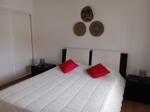 ein Schlafzimmer mit einem weißen Bett mit zwei roten Kissen in der Unterkunft Casa Amarela in Bolembre de Baixo