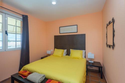 a bedroom with a bed with yellow sheets and a window at Villa Montaña Negra III in San Bartolomé de Tirajana