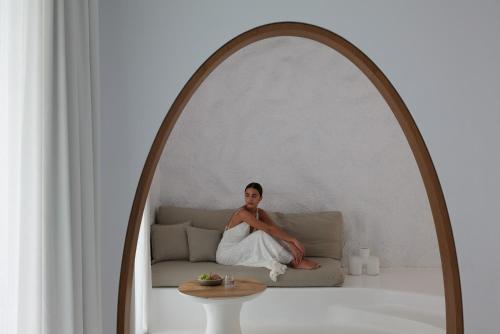 a man sitting on a couch under an archway at Mykonos Earth Suites in Mýkonos City