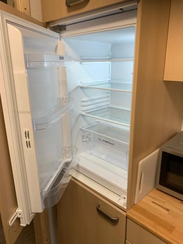 an empty refrigerator with its door open in a kitchen at Jermerstein-Häuschen in Braunlage